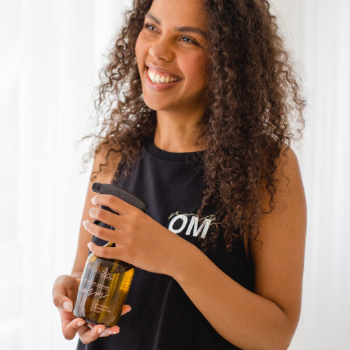 Model mit schwarzem "rock Om" Shirt hält das Yoga Love Shop Matten- und Raumspray im Zerstäuber in der Hand